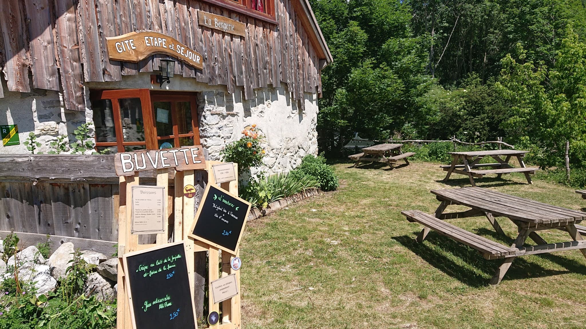 L'enseigne de la buvette et les tables de pique-nique devant le gîte